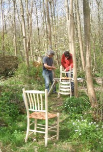Hans and Fransisco applying wych elm bark to their chairs, surrounded by spring flowers.